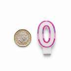 Pink glitter number 0 birthday candle beside a £1 coin on white background showing product scale