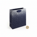 Navy ombre medium gift bag with silver dot pattern placed beside a £1 coin on white background to show size
