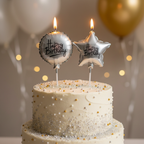 Silver foil circle and star birthday candles lit and glowing on a beautifully decorated birthday cake