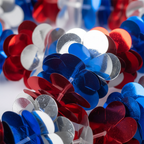 Extreme macro close-up of metallic red, white and blue Hawaiian lei foil shimmer petals catching studio light