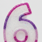 Extreme macro close-up of pink glitter number 6 candle showing pearlescent iridescent glitter texture, hot pink border and purple outline detail