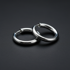 Extreme macro close-up of silver chrome clip-on fake hoop piercing rings showing metallic chrome finish, clip-on mechanism detail and circular hoop shape in sharp focus with soft bokeh background