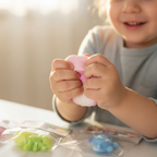 Child's hands authentically squeezing a soft pink squishy toy in a candid joyful moment of sensory play