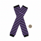 Flat lay of womens purple and black striped tights beside a British pound coin to show scale on white background