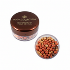 Body Collection Bronzing Pearls 50g — studio hero shot on white background showing open jar with terracotta, golden-sand and espresso shimmer pearls and chocolate brown metallic lid