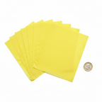 Yellow tissue paper sheets fanned out beside a British pound coin to show 50cm x 75cm scale, flat lay on white background