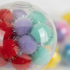 Extreme macro close-up of squishy pom pom ball showing clear stretchy TPR shell texture and soft colourful pom pom filling detail