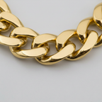 Extreme macro close-up of chunky gold chain necklace links showing high-shine metallic finish and craftsmanship