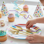 Child reaching for gold plastic spoon at a colourful kids birthday party with cupcakes and party hats