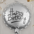 Extreme macro close-up of silver foil birthday candle showing metallic chrome texture and Happy Birthday script detail