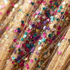 Extreme macro close-up of multi-colour glitter particles on hair strands showing rainbow sparkle texture
