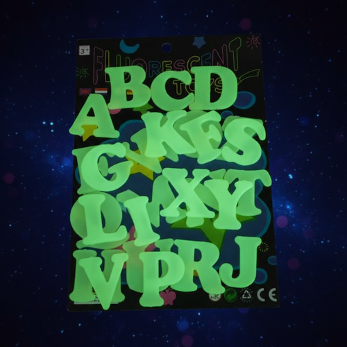 Glow in the dark stick on alphabet letters set glowing luminous green on a deep midnight blue starry background