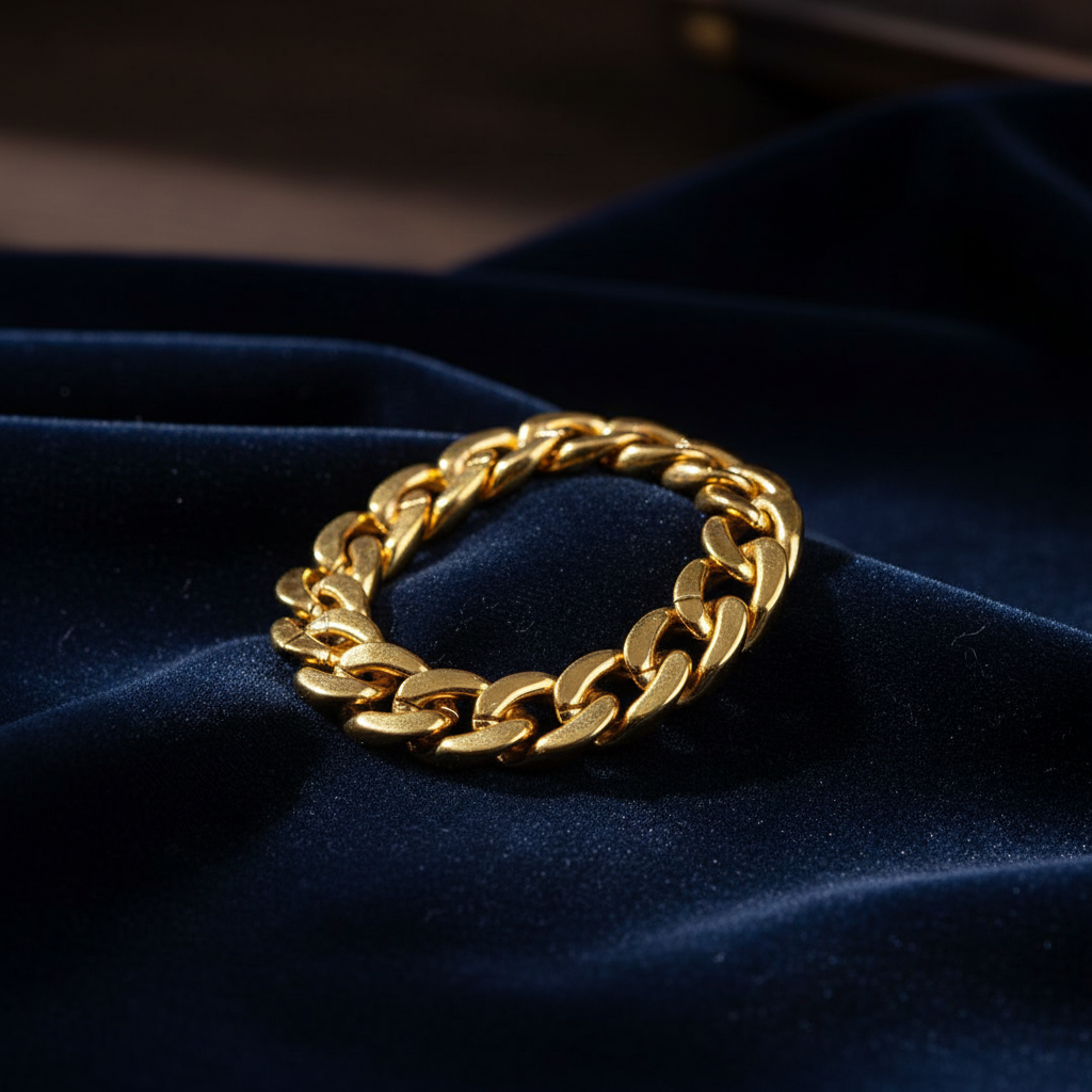 Chunky gold bracelet draped over dark velvet surface with moody studio lighting
