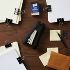 Flat lay of easy grip heavy duty stapler with documents, pen and notebook on dark walnut desk