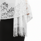 Close-up detail of pure white lace floral pattern and tassel fringe on evening pashmina shawl