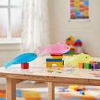 Pink, blue and yellow-green squishy fish toys arranged on a kids playroom shelf with natural window light