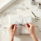 Hands wrapping elegant gift with silver organza ribbon creating perfect bow