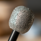 Extreme macro close-up of silver glitter microphone head showing individual glitter particles and sparkle texture detail