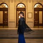 Elegant woman wearing black lace pashmina shawl on steps of grand theatre at night