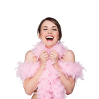 A woman with dark hair smiling broadly while wearing a fluffy light pink feather boa around her neck and shoulders, set against a plain white background.