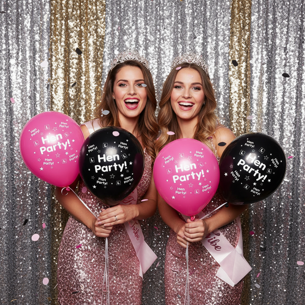 Two women at a hen party photobooth posing with pink and black latex balloons wearing Bride Tribe accessories