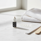 Technic Essentials Nail Glue 2ml on marble vanity beside false nails and nail file — natural window light lifestyle shot