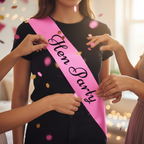 Close-up of pink hen party sash with friends adjusting it amid falling pink and gold confetti