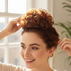 Woman styling her hair with a warm auburn copper curly messy hair bun clip-in hairpiece shade 33/30 Sunrose, candid natural moment with bokeh background