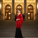 Elegant woman wearing red lace pashmina shawl on steps of grand theatre at night