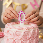 Hands placing pink glitter number 0 candle onto a white birthday cake with pink frosting