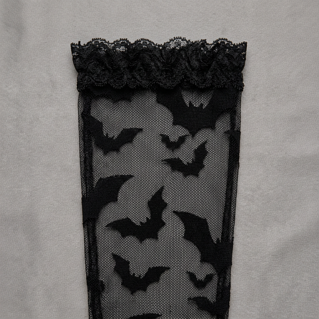 Close-up of black bat motifs in the sheer lace glove fabric and cuff.