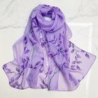 Womens purple chiffon scarf with dark purple botanical leaf print, elegantly draped on white marble surface - studio product shot