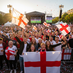 England football fans waving St George Cross flags at an outdoor watch party, joyful crowd, golden light