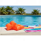Orange Intex inflatable arm bands resting on pool edge with towel and sunscreen in summer