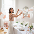 Woman hanging Sparkling Fizz Birthday banner at elegant rose gold and white party celebration