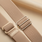 Extreme macro close-up of Adorn 1.2cm beige adjustable bra strap showing elastic weave texture, slide adjuster and clip hook detail