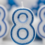 Extreme macro close-up of blue glitter border texture on number 8 birthday candle, raking side light