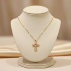 Elegant gold cross pendant necklace with stainless steel chain on luxury velvet display stand