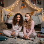 Two teenage girls at a sleepover laughing as one pranks the other with joke sneezing powder