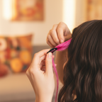 Candid shot of hands clipping in a hot pink Stargazer hair extension, 85mm bokeh background