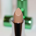 Extreme macro close-up of W7 Tea Tree Concealer Stick showing creamy warm beige bullet texture and metallic green casing with engraved W7 logo detail