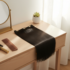 Deep off-black one piece straight clip-in hair extension draped over a minimalist vanity in soft natural window light