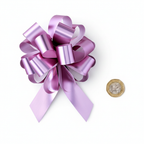 Flat lay of large pink pull bow beside a £1 coin on white background showing 6-inch scale, overhead lighting