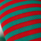 Extreme close-up macro of red and green striped tights fabric showing soft stretchy knit texture and material quality