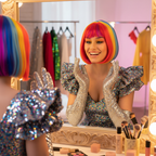 Woman in rainbow bob wig smiling at mirror in diva costume — instant party transformation