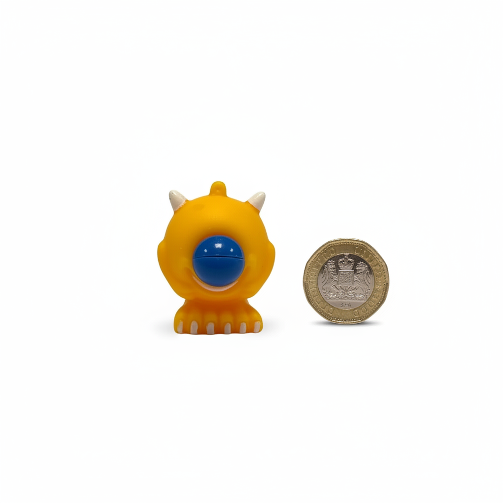 Google Eyed Squeeze Monster 6cm size comparison flat lay next to UK pound coin on white background
