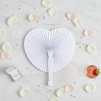 White heart paper fan flat lay on marble with rose petals and pearl decorations
