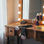 Long black fishnet net gloves laid on a vintage 80s dressing table with mirror, jewellery and hairspray props, natural window light