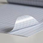 Extreme macro close-up of Tiger clear self-adhesive book cover film showing transparent material, navy grid lines and adhesive layer