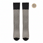 Black fishnet thigh high stockings flat lay with British pound coin for scale on white background